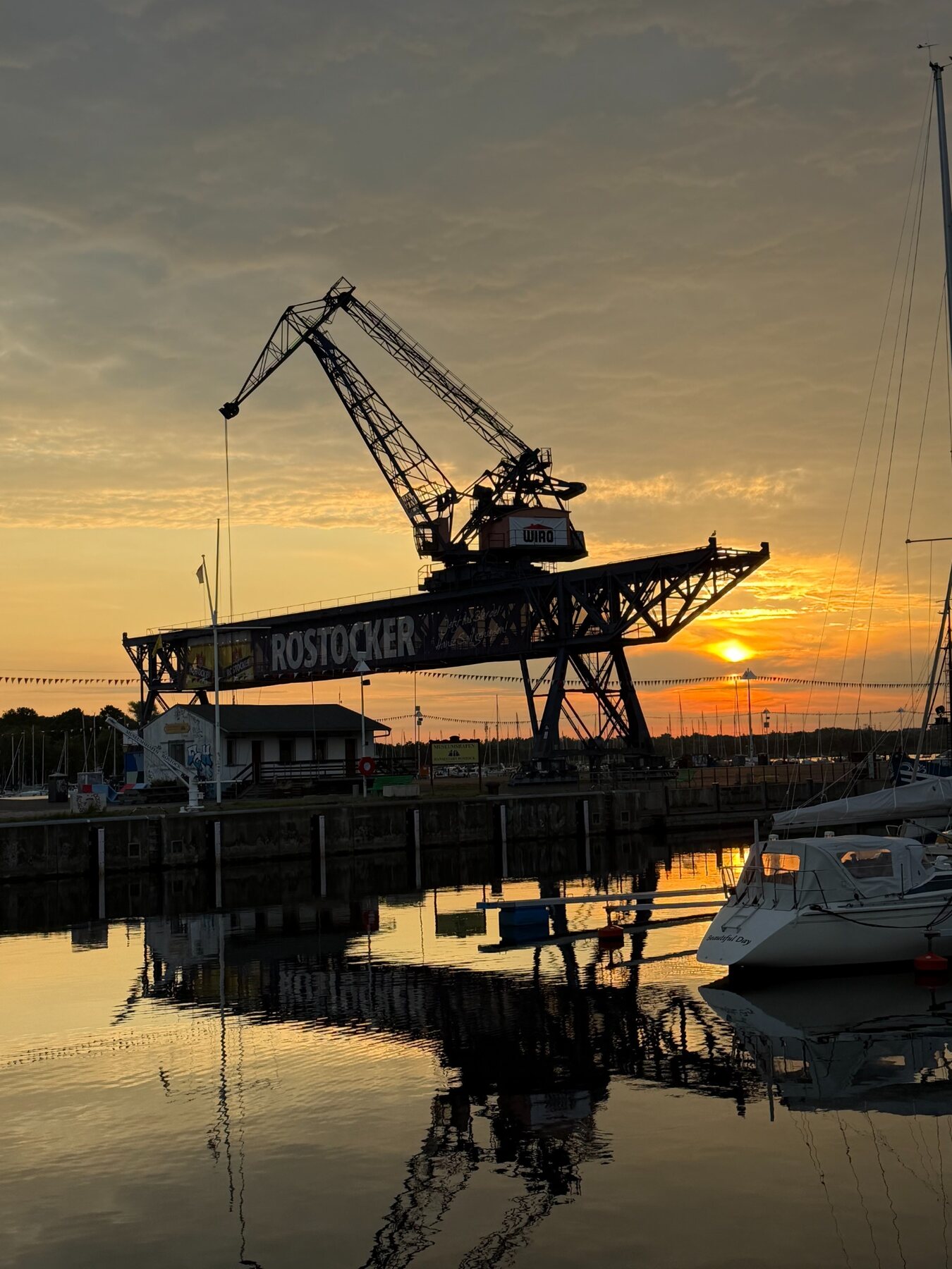 Historischer Rostocker Hafenkran, Segelboot und Spiegelung im Wasser
